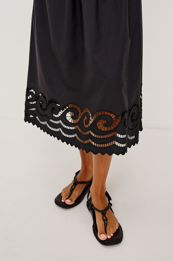 Anadia Maxi Dress in Poplin With Soutached Swirl Shoulder Straps, Ruched Bust, Smocked Empire Waist, and Scalloped Ladder Embroidered Hem in Black Colorway - Lower Body Close Up View Featured on Model