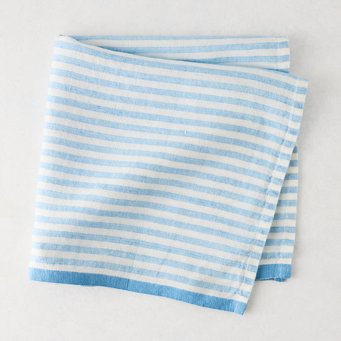 Folded blue and white ticking stripe linen napkin with a thicker blue border.