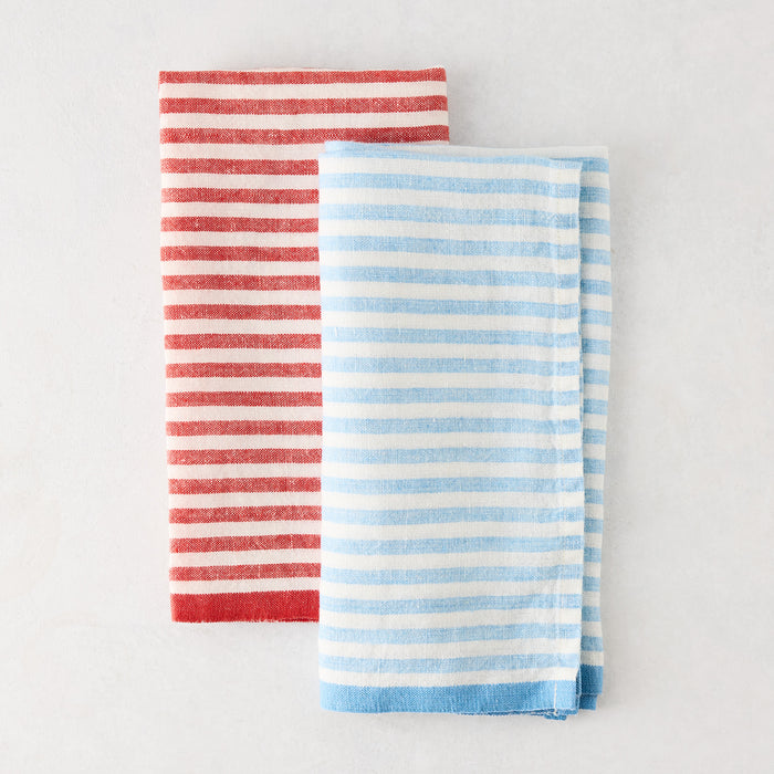 Folded blue and white ticking stripe linen napkin next to a red striped napkin.