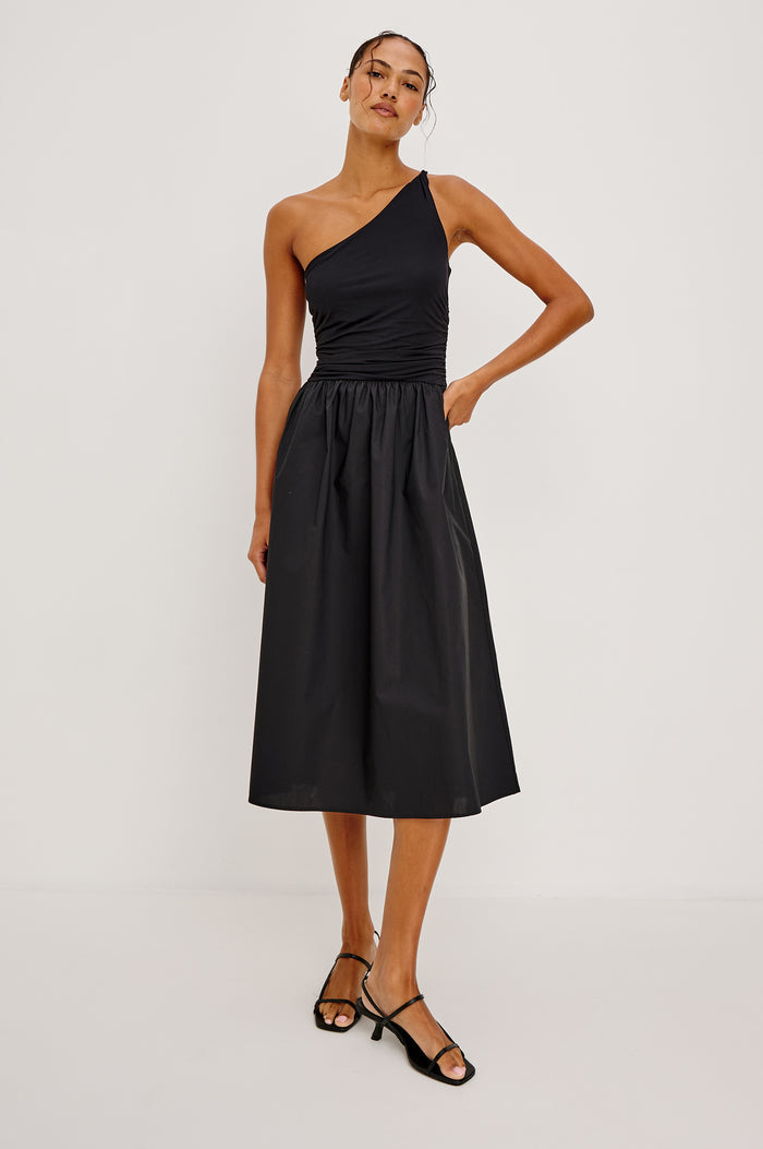 Chayana Midi Dress in Jersey With One-Shoulder Twist Strap Neckline, Waist Shirring, Side Pockets, Poplin Skirt in Black Colorway - Full Body Front View Featured on Model