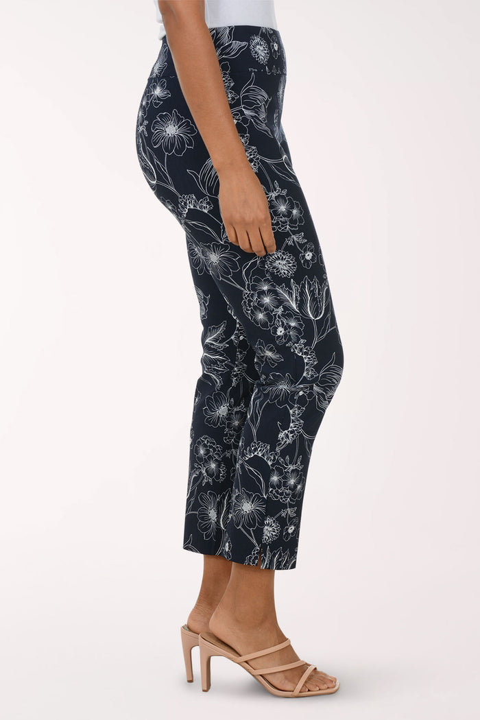 Navy pants with white floral pattern worn by a person on a white background