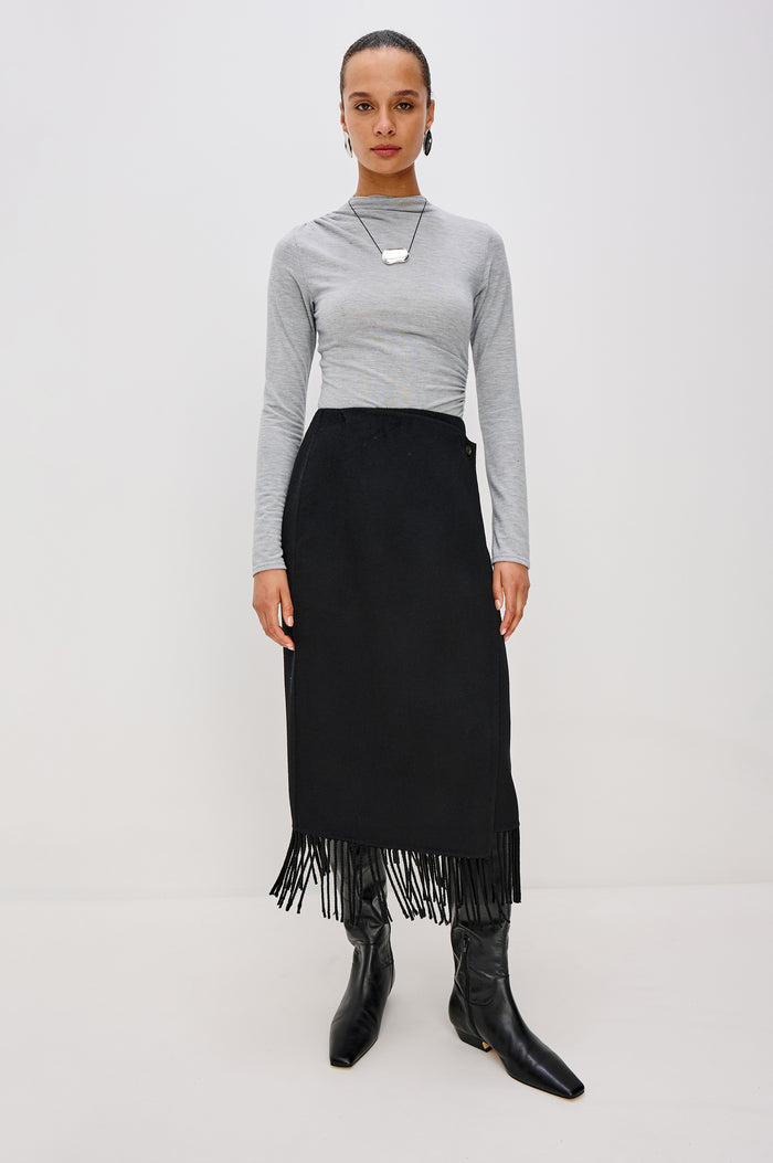 Odette Midi Skirt in Wool Blend With Wrap Design, Hidden Side Button Closure, and Fringe Hem in Black Colorway - Full Body Front View Featured on Model