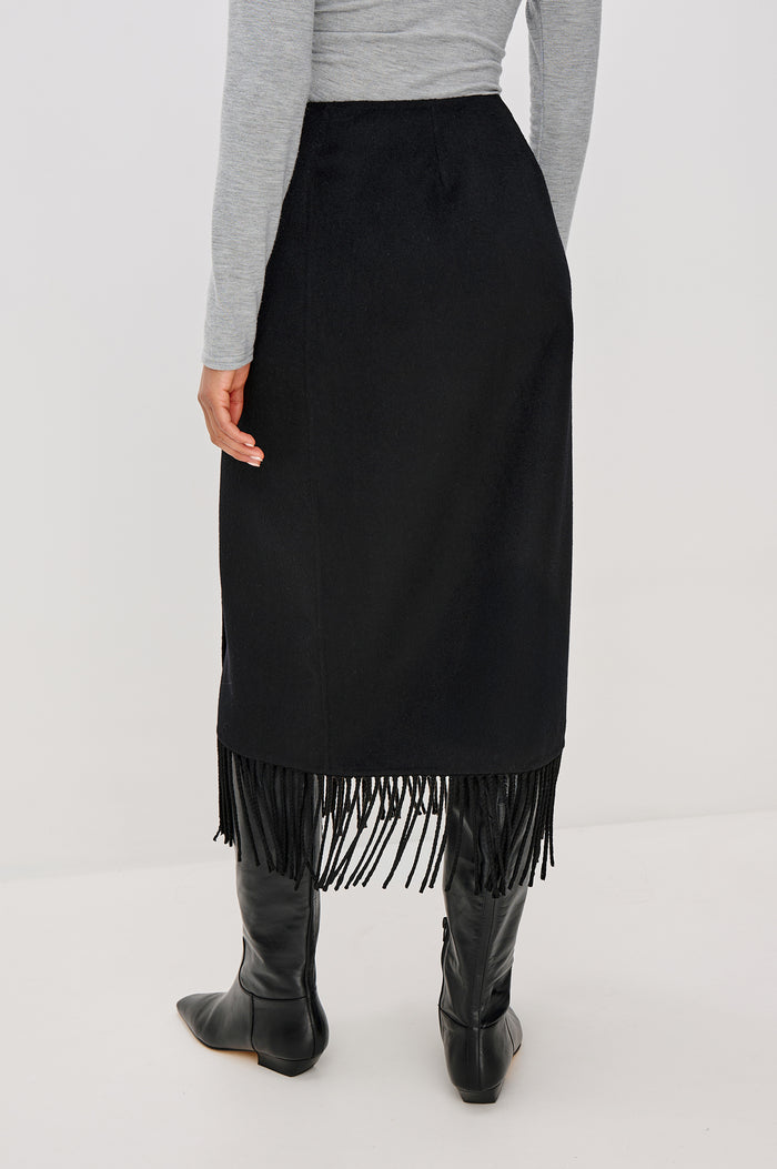 Odette Midi Skirt in Wool Blend With Wrap Design, Hidden Side Button Closure, and Fringe Hem in Black Colorway - Lower Body Back View Featured on Model