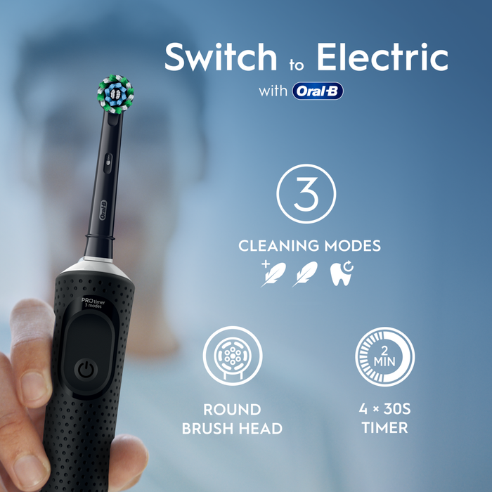 Oral-B Vitality PRO black electric toothbrush held by hand on blue background, text reads "Switch to Electric with Oral-B, 3 Cleaning Modes, Round Brush Head, 4x30S Timer"