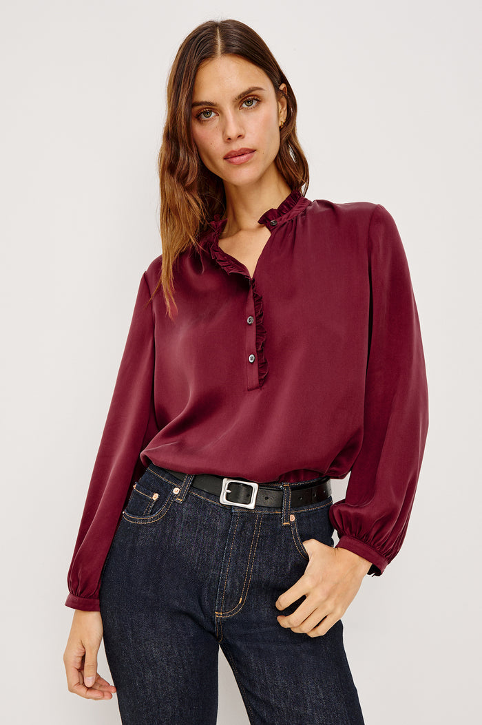 Sien Top in Silk Charmeuse With Ruffled High Neckline, Half Button Placket, and Long Billowing Sleeves With Fitted Cuffs in Garnet Colorway - Upper Body Front View Featured on Model