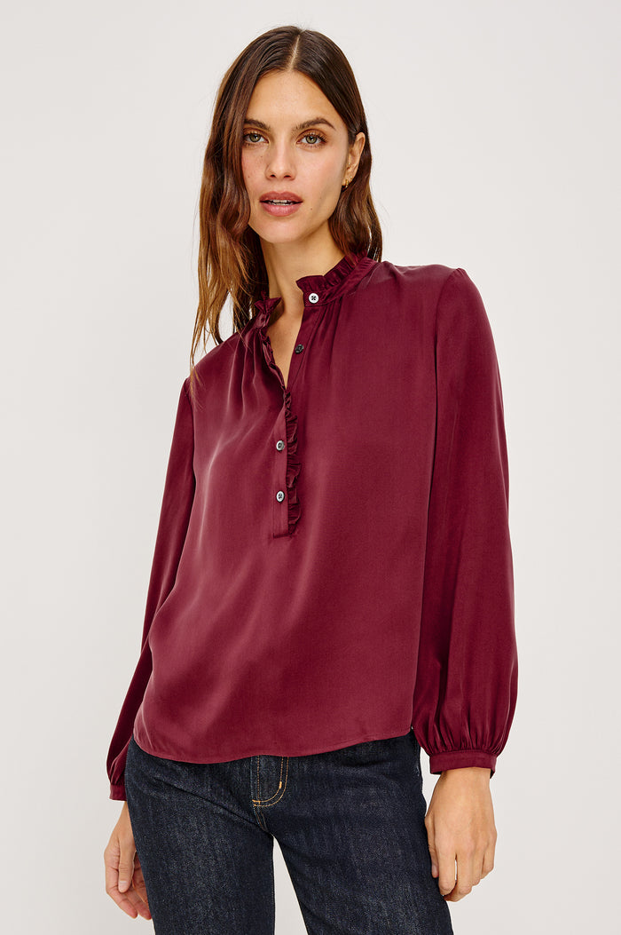 Sien Top in Silk Charmeuse With Ruffled High Neckline, Half Button Placket, and Long Billowing Sleeves With Fitted Cuffs in Garnet Colorway - Upper Body Front View Featured on Model