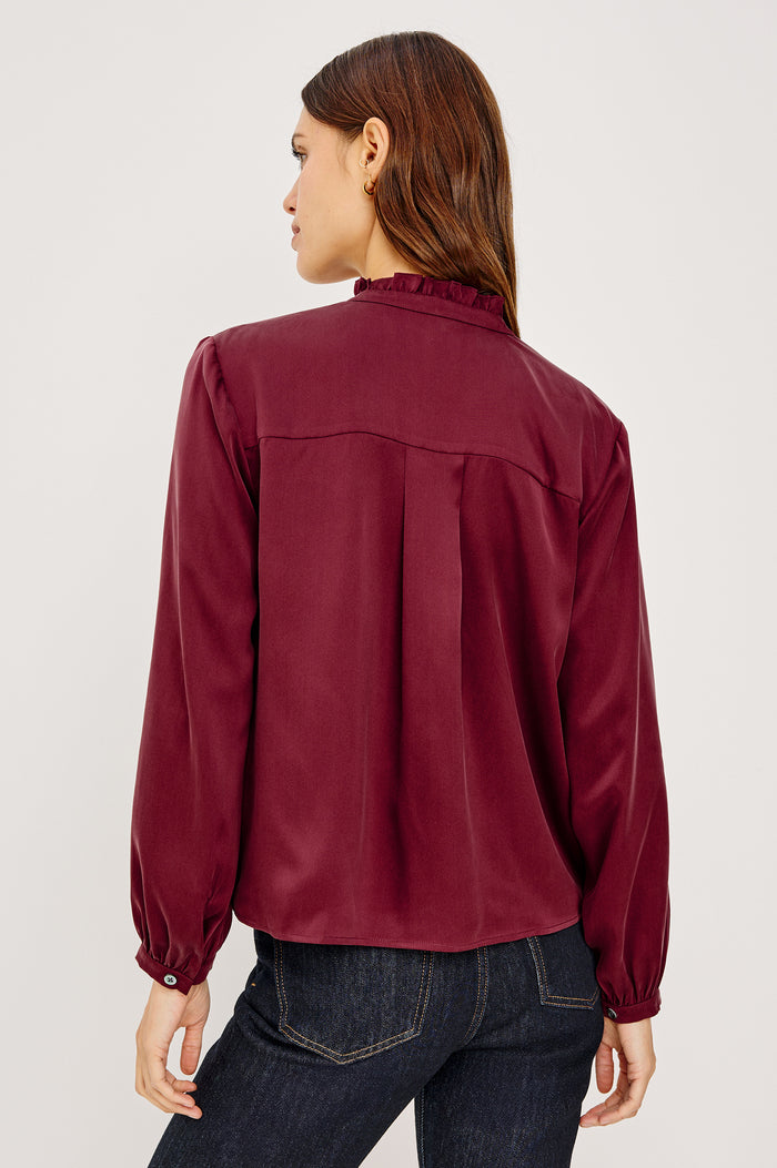 Sien Top in Silk Charmeuse With Ruffled High Neckline, Half Button Placket, and Long Billowing Sleeves With Fitted Cuffs in Garnet Colorway - Upper Body Back View Featured on Model